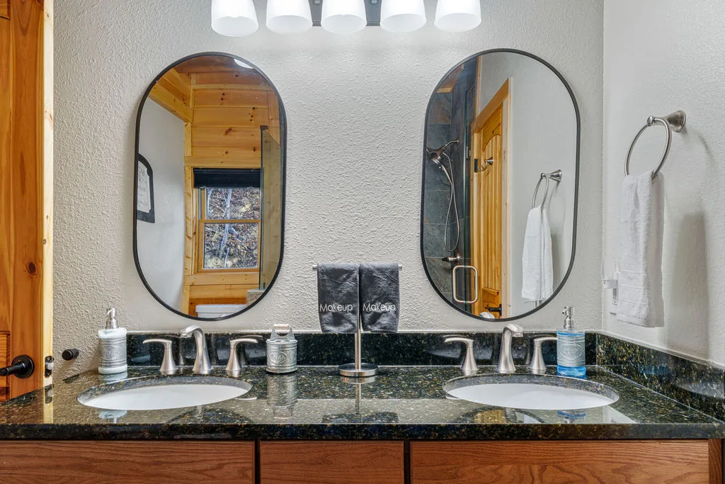 Bathroom with a double granite vanity and two oval mirrors