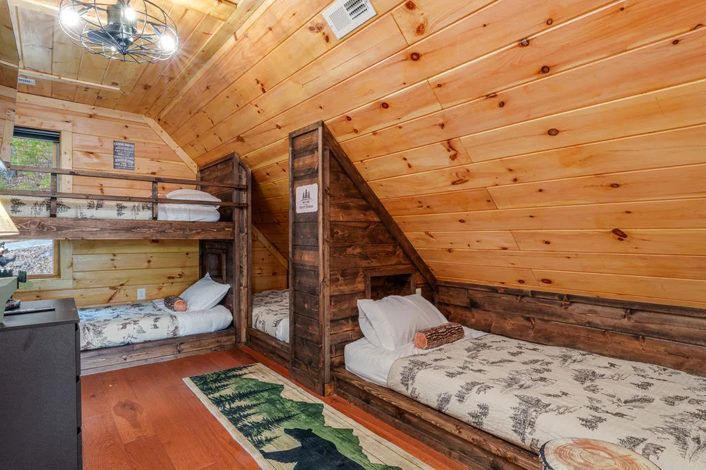 Bunk room with custom-built twin XL bunk beds under a sloped pine ceiling