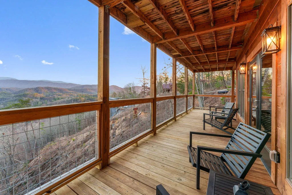 Covered deck lined with rocking chairs facing the mountains