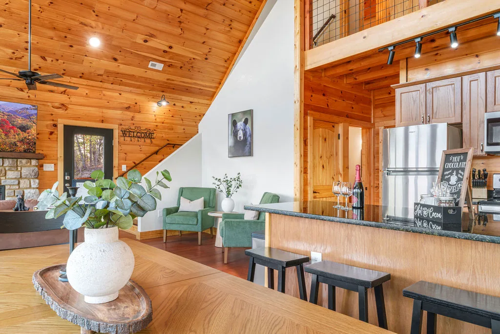 Open-plan dining area and kitchen with a long table, island seating, and warm pine walls