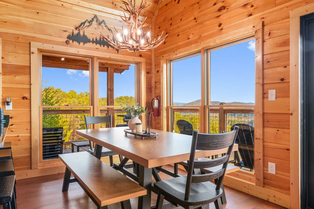Dining table set beneath a mountain-motif chandelier with windows overlooking the Smokies