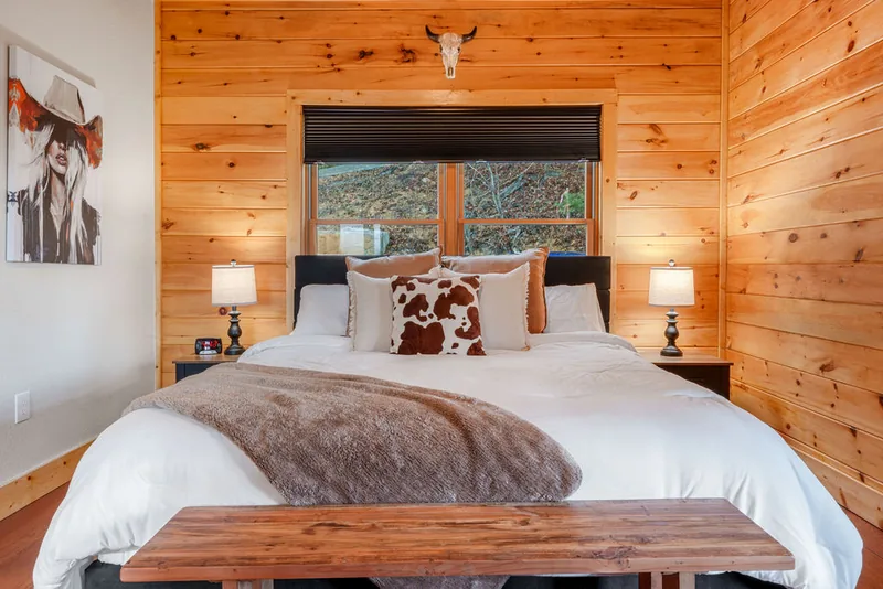 King bedroom with a wood-framed bed and pine plank walls