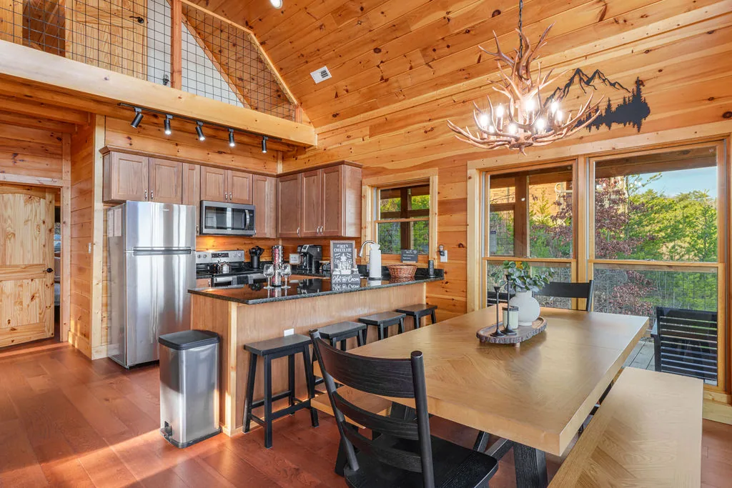Wide view of the cabin kitchen with knotty pine cabinets and windows above the sink