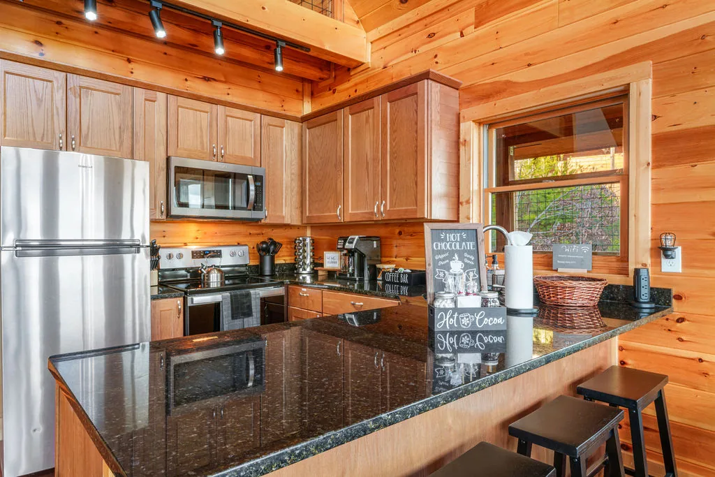 Kitchen island with granite counters, bar stools, and stainless steel appliances
