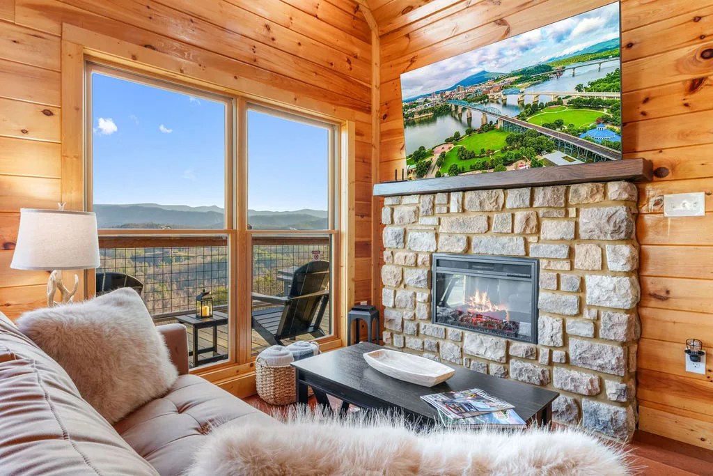 Sofa and armchairs arranged around the fireplace with the mountain ridgeline visible through the windows