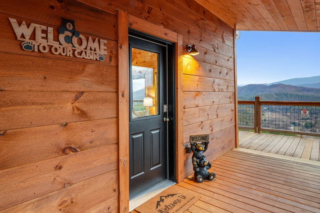 Front entry of the cabin with a welcome sign beside the door